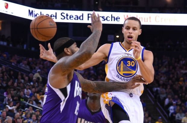 December 22, 2014; Oakland, CA, USA; Golden State Warriors guard Stephen Curry (30) passes the basketball against Sacramento Kings center DeMarcus Cousins (15) during the third quarter at Oracle Arena. The Warriors defeated the Kings 128-108. Mandatory Credit: Kyle Terada-USA TODAY Sports